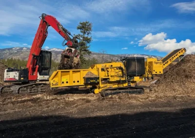 Skemxist Solutions Equipment Power Clam Hydraulic Log Loader Feeding a Wood Waste Grinder